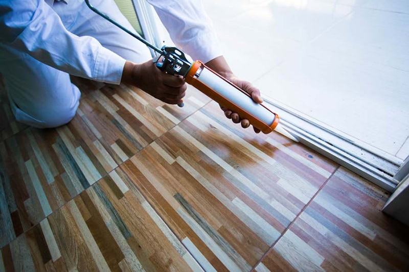 Construction workers install doors - windows and use silicon and sealant.