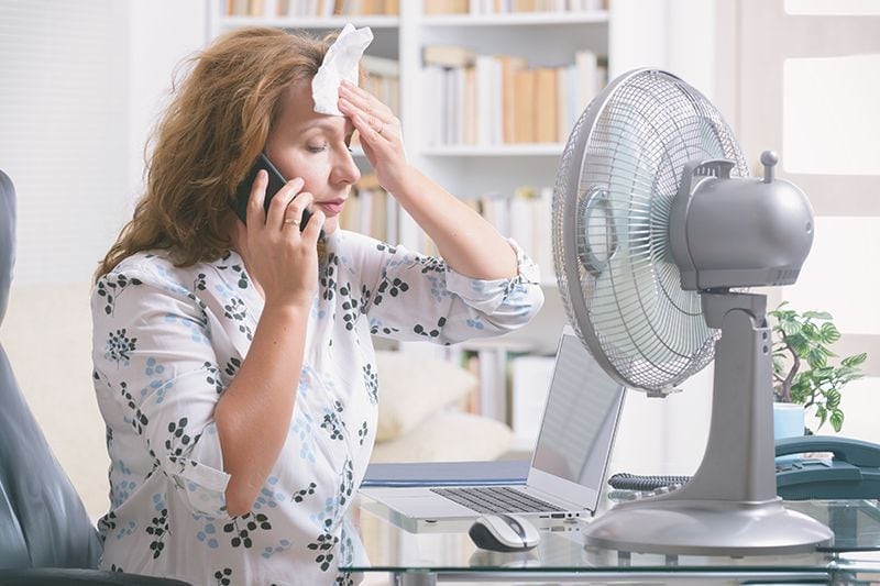 Image of someone sitting in front of fan. When Do I Replace My Air Conditioner?