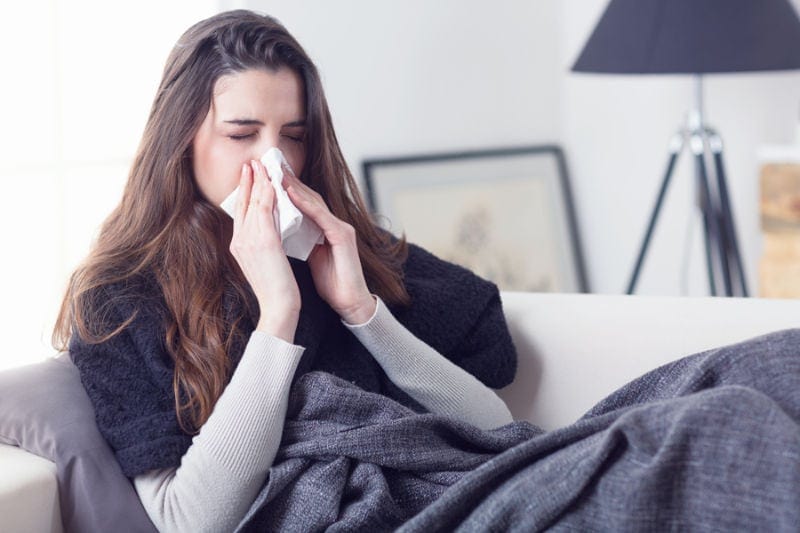 Woman sneezing nose with tissue