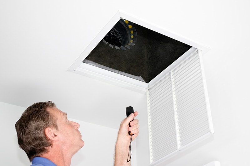 Man Looking at HVAC System in Attic